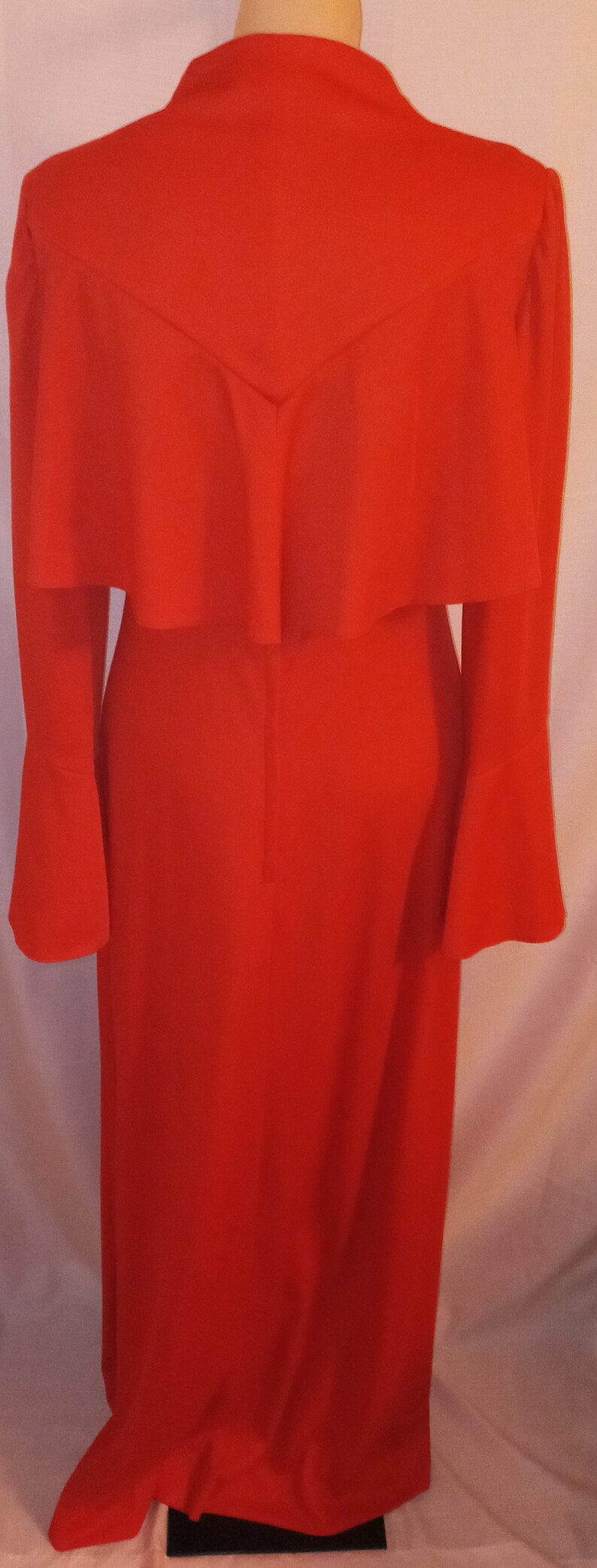 May include: A long-sleeved red dress with a ruffled neckline and bell sleeves.