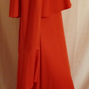 May include: A long, red dress with a ruffled collar and long sleeves. The dress has a fitted bodice and a flowing skirt.