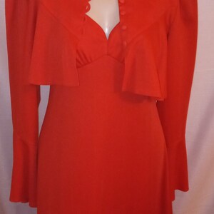 May include: A red dress with a matching jacket. The dress has a sweetheart neckline and the jacket has a scalloped collar and button closure.