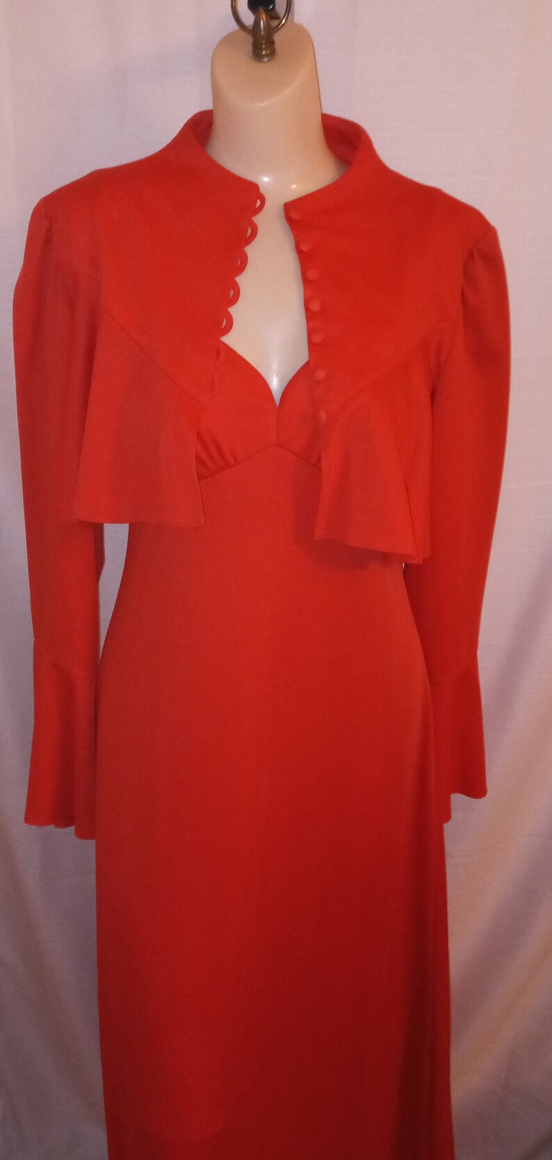 May include: A red dress with a matching jacket. The dress has a sweetheart neckline and the jacket has a scalloped collar and button closure.