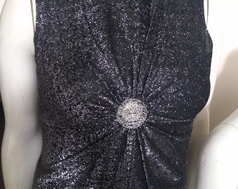 May include: A sleeveless, silver and black sparkly top with a large, silver, decorative button in the center.