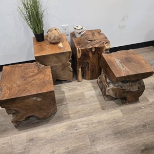 May include: Three square-shaped side tables crafted from natural brown wood stumps. Each table features a flat top surface with visible wood grain patterns and irregular, organic edges along the sides, showcasing the raw texture of the tree trunk.