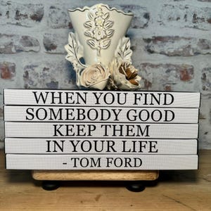 May include: A stack of five white books with black text. The text reads "When you find somebody good keep them in your life - Tom Ford".
