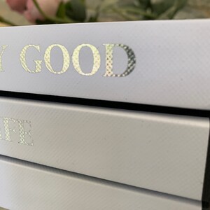 May include: A stack of three light blue books with silver foil lettering. The top book says "Very Good", the middle book says "Life", and the bottom book is not visible.