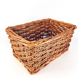 May include: A rectangular woven wicker basket with a brown and tan color scheme. The basket is made of natural materials and has a rustic look.