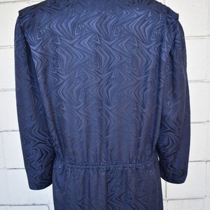 May include: A long-sleeved navy blue dress with a geometric pattern. The dress has a gathered waist and a v-neck.