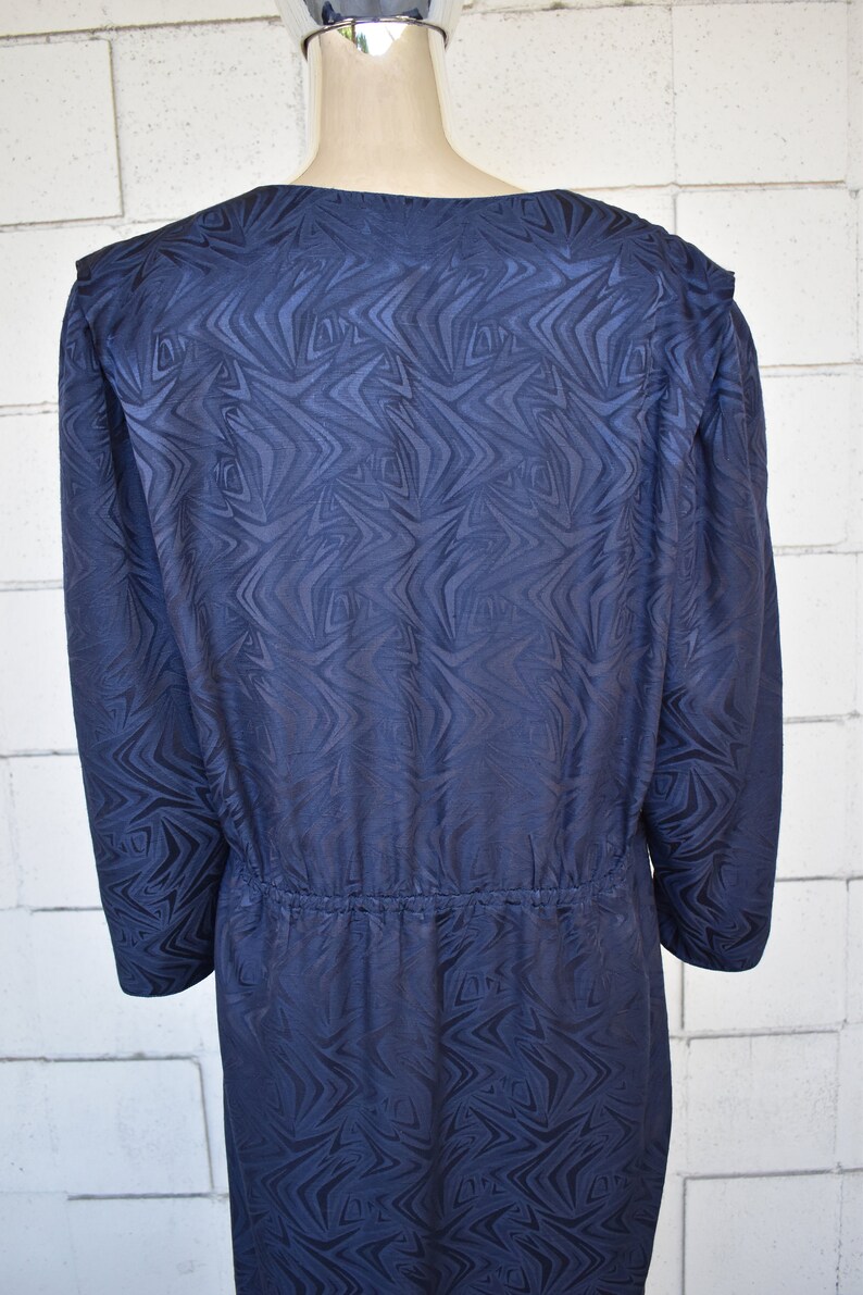 May include: A long-sleeved navy blue dress with a geometric pattern. The dress has a gathered waist and a v-neck.