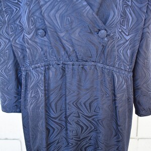 May include: A dark blue wrap dress with a swirling pattern. The dress has a V-neckline and a cinched waist.