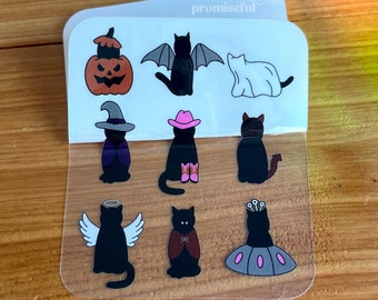 May include: A sheet of clear stickers featuring nine black cat illustrations in various Halloween costumes. The costumes include a witch, a vampire, a ghost, a cowboy, a devil, an angel, a pumpkin, and a queen. The stickers are printed with the text "promiseeful".