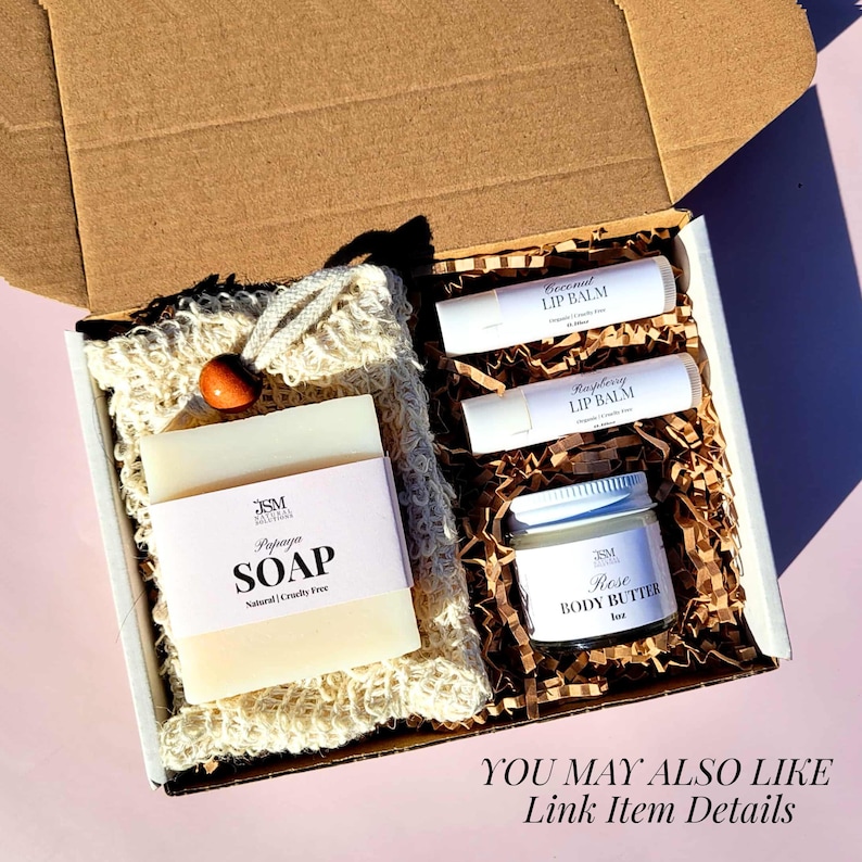 May include: A gift box containing soap, lip balm, and body butter. The soap is labeled "Papaya Soap" and is natural and cruelty-free. The lip balms are labeled "Coconut Lip Balm" and "Raspberry Lip Balm". The body butter is labeled "Rose Body Butter".