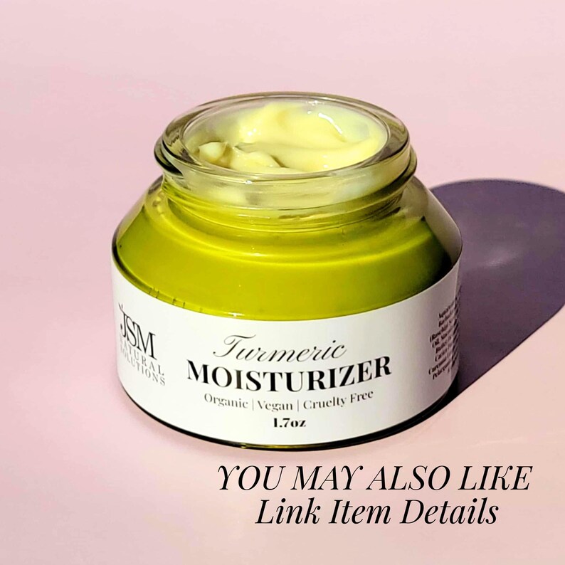 May include: A jar of turmeric moisturizer with a yellow-green hue. The product is in a clear glass jar with a black lid. The label reads "Turmeric Moisturizer" and includes the text "Organic | Vegan | Cruelty Free" and "1.7oz".