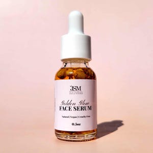 May include: A clear glass bottle of Golden Glow Face Serum with a white dropper top. The label reads "JSM Natural Solutions" and "Natural | Vegan | Cruelty Free". The bottle contains a golden liquid and is 0.5 oz.