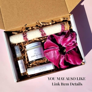 May include: A gift box filled with beauty products. Includes a jar of Rose Body Butter, a tube of bath salts with rose petals, a raspberry lip balm, a toning mist spray, and a magenta velvet scrunchie.