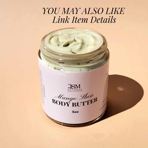 May include: A clear glass jar filled with light green Mango Shea Body Butter. The jar has a white label with black text that reads "JSM Natural Solutions Mango Shea Body Butter 4oz". The text "YOU MAY ALSO LIKE Link Item Details" is at the top.