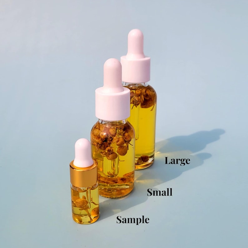 May include: Three glass dropper bottles of varying sizes, filled with a yellow liquid and dried botanicals. The bottles have white and pink tops. The smallest bottle is labeled "Sample", the others are labeled "Small" and "Large".