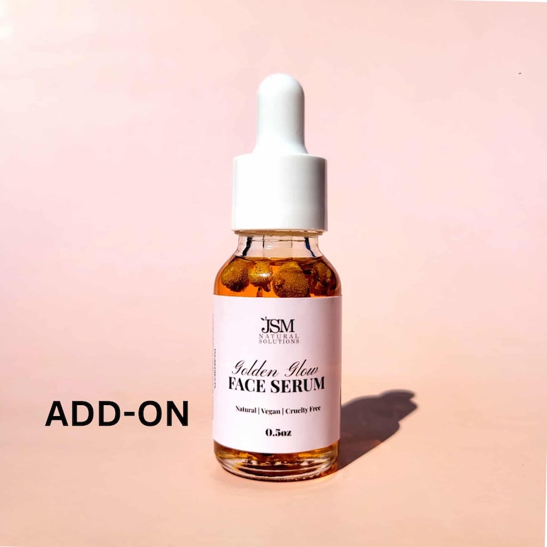 K&ouml;nnte beinhalten: Eine kleine Glasflasche Golden Glow Face Serum mit wei&szlig;em Tropfaufsatz. Die Flasche hat ein wei&szlig;es Etikett mit dem Text "Golden Glow FACE SERUM" und "Natural | Vegan | Cruelty Free". Die Flasche enth&auml;lt 14.7 ml Serum. Das Wort "ADD-ON" ist links aufgedruckt.