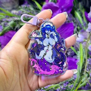 Op de afbeelding: Een heldere acryl sleutelhanger met een anime-stijl personage met blauw haar in een dienstmeisje outfit, die een dienblad vasthoudt. Het ontwerp bevat paarse en roze tentakels en een lila sluiting. De achtergrond is gevuld met paarse bloemen.