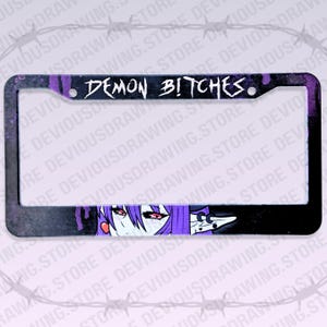May include: A rectangular black number plate frame featuring a purple paint splatter effect and the text DEMON BITCHES in a jagged white font. The bottom section displays a graphic of a purple-haired character with red eyes and pointed ears.