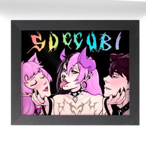 May include: Framed art print featuring a colorful illustration of three figures with horns and pink hair. The word "SUCCUBI" is written in a rainbow font across the top. The figures are set against a black background.