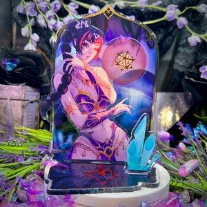 Op de afbeelding: Een acryl display met een geïllustreerd personage met donker haar in een hoge paardenstaart, gekleed in een paars en goudkleurig harnas. De achtergrond bevat een gouden twintigzijdige dobbelsteen en blauwe kristallen op een donkere voet.