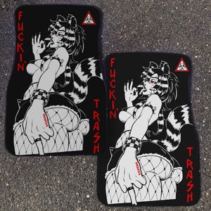 May include: Pair of black car floor mats featuring a stylized illustration of a raccoon-like character with red eyes and a striped tail. The text "FUCKIN' TRASH" is printed in red. A biohazard symbol is also present.
