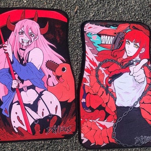 Puede incluir: Dos alfombrillas para coche con ilustraciones de estilo anime. Una presenta un personaje de pelo rosa con cuernos y una guada&ntilde;a, la otra un personaje de pelo rojo con una motosierra. Ambas alfombrillas tienen la palabra "DEVIOUS" impresa.