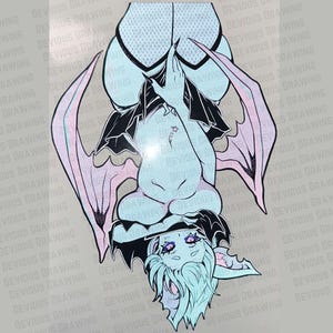 May include: A stylized illustration of a bat-like creature, rendered in soft pastel colors. The artwork features a light blue body, black accents, and pink wings. The creature is depicted upside down, with a whimsical expression and detailed linework.