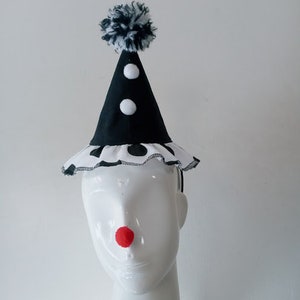 K&ouml;nnte beinhalten: Ein schwarz-wei&szlig;er Clownshut mit einem wei&szlig;en Bommel oben. Der Hut hat einen schwarz-wei&szlig;en Tupfenrand und eine rote Filznase.
