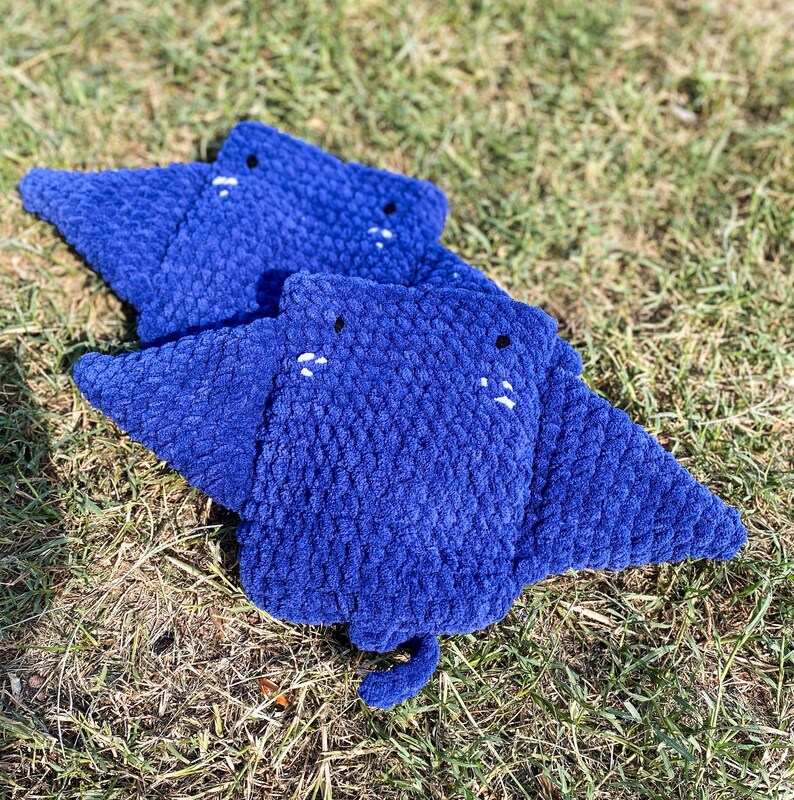 Op de afbeelding: Drie blauwe gehaakte roggen knuffels met witte geborduurde ogen. De knuffels zijn gestapeld met de grootste onderaan.
