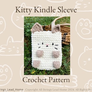 Può includere: Schema a uncinetto per una custodia Kindle a forma di gattino bianco. La custodia ha orecchie, zampe e baffi marroni. Lo schema è disponibile per il download.