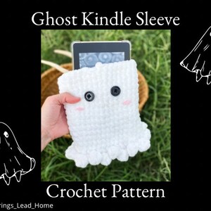 May include: White crocheted ghost Kindle sleeve with black button eyes and pink blush. The sleeve is designed to fit a Kindle e-reader. "Ghost Kindle Sleeve Crochet Pattern" is written in black text at the bottom of the image. "@All_Strings_Lead_Home" is written in black text at the bottom of the image.