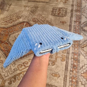 Op de afbeelding: Een blauwe gehaakte tablet hoes in de vorm van een mantarog. De hoes heeft twee witte ogen en een witte mond.