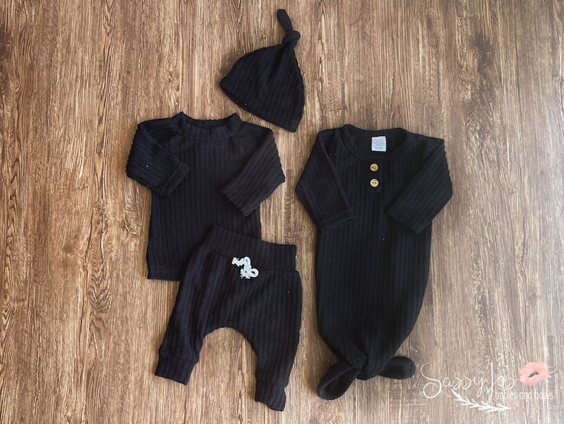 Gender neutral black coming home outfit and gown set. Black brushed waffle knit 3 piece outfit, long sleeve top, pants, tie hat, and knotted gown with buttons. Black newborn clothing