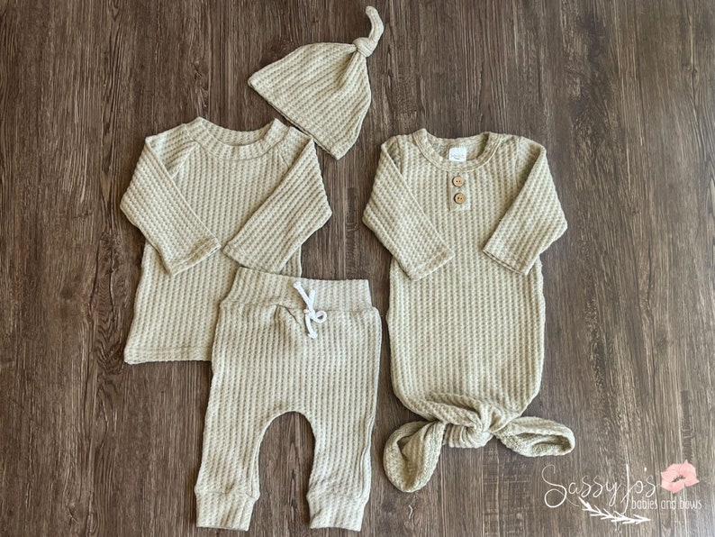 Gender neutral coming home outfit 4 piece bundle. Sandy beige color. Bundle includes a super soft brushed waffle knit long sleeve top, pants, tie hat, and a 0-3M matching waffle knot knotted baby gown with two wooden buttons.