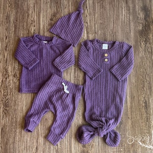 Newborn Baby girl knotted gown and coming home outfit set. Purple waffle knit baby girl outfit with long sleeve shirt, pants, tie hat, and knotted baby gown with two wooden buttons.