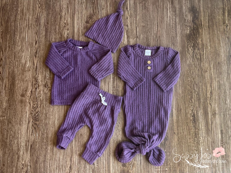 Newborn Baby girl knotted gown and coming home outfit set. Purple waffle knit baby girl outfit with long sleeve shirt, pants, tie hat, and knotted baby gown with two wooden buttons.