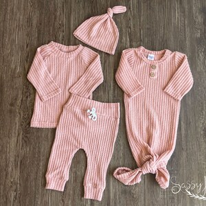 Baby girl knotted gown and coming home outfit set. Pink waffle knit baby girl outfit with long sleeve shirt, pants, tie hat, and knotted baby gown with two wooden buttons.