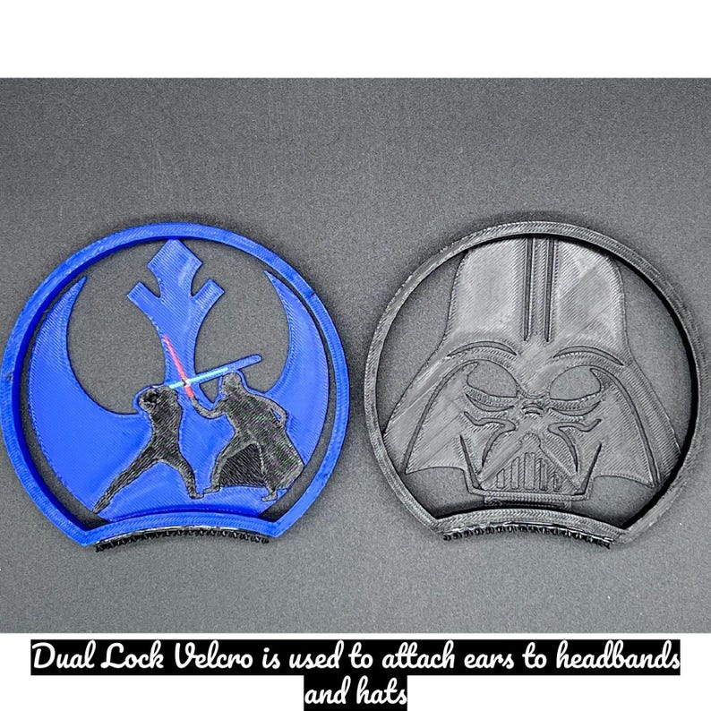 Puede incluir: Dos accesorios para las orejas con tem&aacute;tica de Star Wars impresos en 3D. Uno es azul con un s&iacute;mbolo de la Alianza Rebelde y figuras con sables de luz. El otro es negro y representa el casco de Darth Vader. El texto en la parte inferior dice: Dual Lock Velcro se utiliza para sujetar las orejas a las diademas y sombreros.
