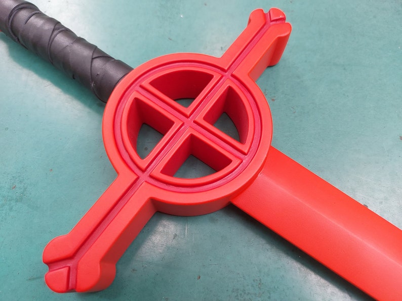May include: A red plastic sword with a circular cross guard. The cross guard has a design of four circles within a larger circle.
