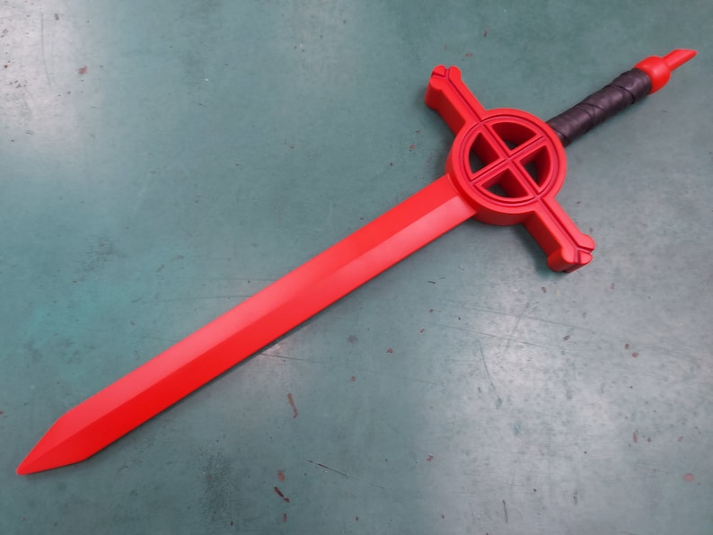 May include: A red plastic sword with a black handle and a circular design on the hilt. The design features a cross within a circle.