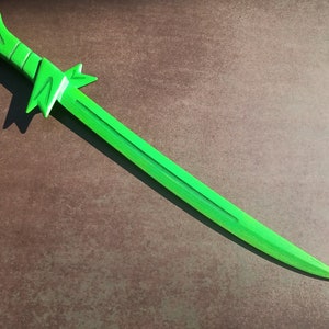 May include: A bright green wooden sword with a decorative handle. The sword is lying on a brown surface.