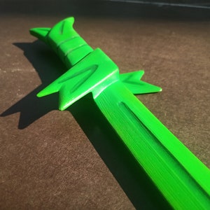 May include: A bright green plastic toy sword with a textured surface and a pointed tip.