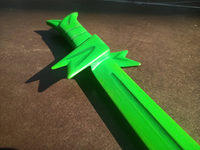 May include: A bright green plastic toy sword with a textured surface and a pointed tip.