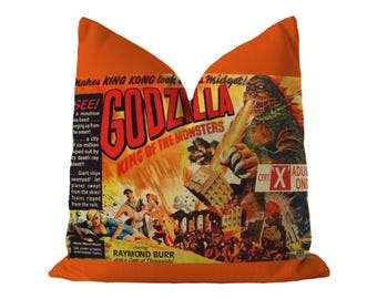 May include: An orange throw pillow featuring a vintage Godzilla King of the Monsters movie poster print. The graphic displays the monster breathing fire over a city, with text including "Makes KING KONG look like a Midget!" and "Raymond Burr."