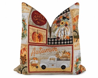 May include: A square throw pillow featuring a patchwork design with autumn-themed illustrations including a white truck with the word Harvest, pumpkins, sunflowers, a bicycle, and text reading Hot Apple Cider, Autumn, and Hello Fall.