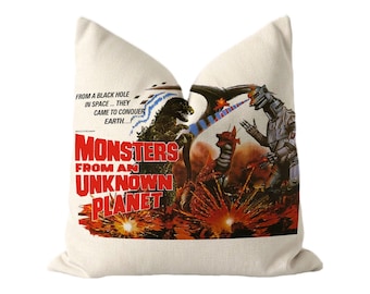 May include: A cream-colored throw pillow featuring a vintage movie poster graphic titled Monsters From An Unknown Planet. The print depicts a dark monster, a red creature, and a silver robot amidst explosions with the text From A Black Hole In Space... They Came To Conquer Earth.