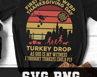 May include: A black t-shirt with a vintage-style graphic design featuring a helicopter dropping turkeys in a city skyline. The text reads "First Annual WKRP Thanksgiving Day" and "Turkey Drop As God is my witness I thought turkeys could fly".
