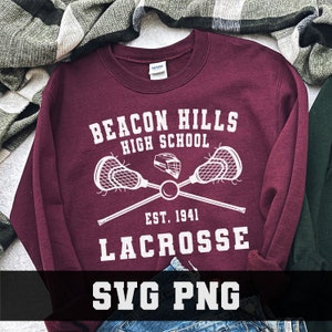 May include: A maroon sweatshirt with white text that reads "Beacon Hills High School Est. 1941 Lacrosse SVG PNG". The text is surrounded by a graphic of two lacrosse sticks crossed with a lacrosse helmet in the center.