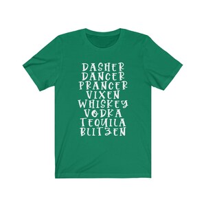 May include: A green t-shirt with white text listing holiday-themed words: Dasher, Dancer, Prancer, Vixen, Whiskey, Vodka, Tequila, and Blitzen. The shirt has short sleeves and a crew neck.
