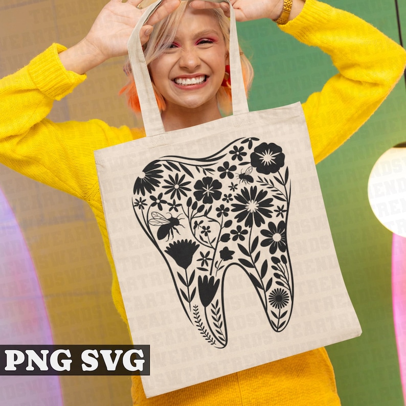 May include: A white tote bag with a black floral design in the shape of a tooth. The design includes bees and flowers.